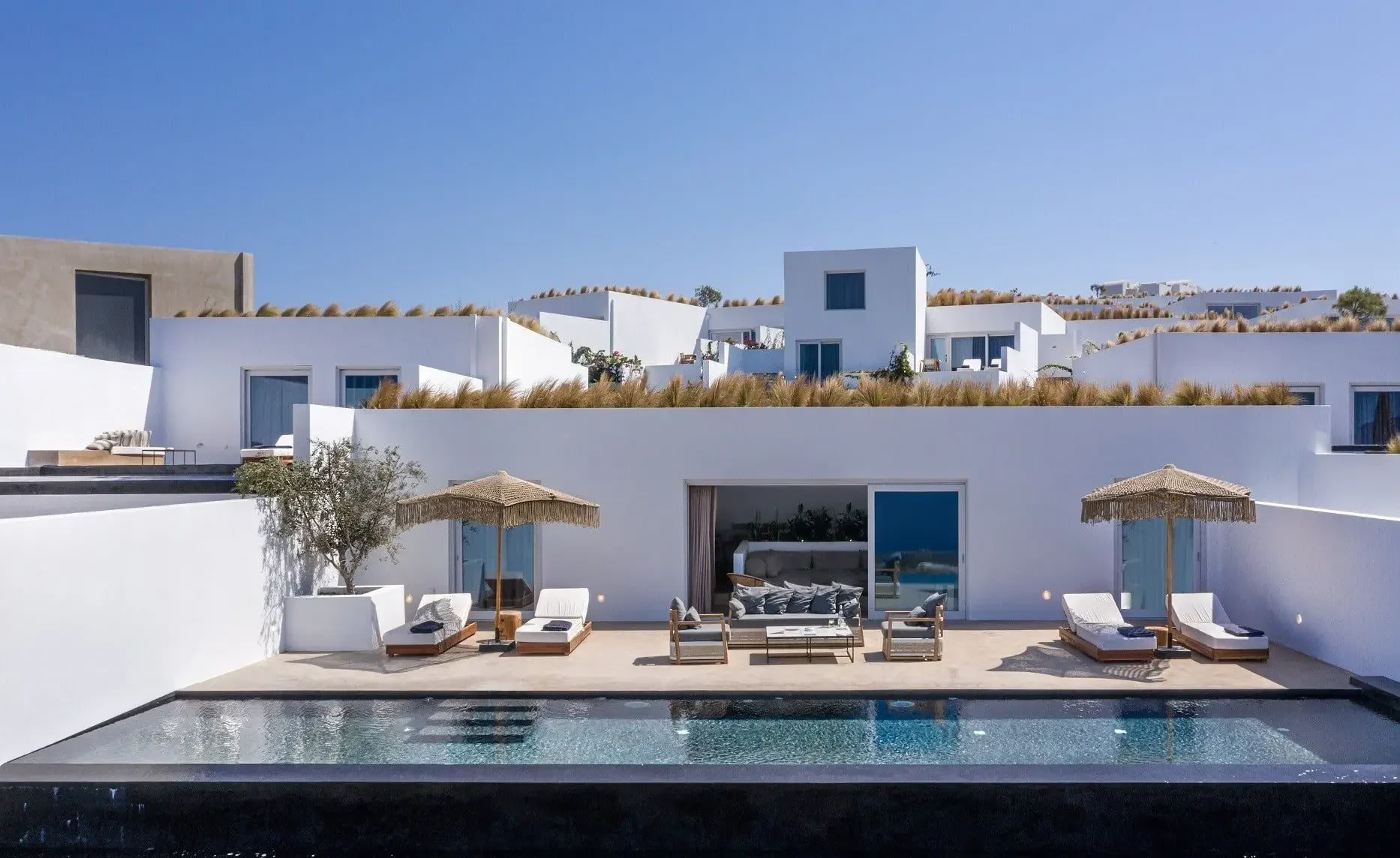 Andronis Arcadia luxury resort in Oia featuring private pool suites, modern Cycladic architecture, and open Aegean Sea sunset views beyond the caldera.