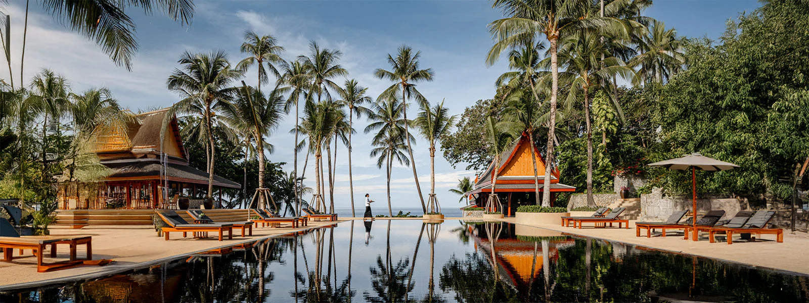Lush garden-framed pavilions at Amanpuri in Phuket, a flagship luxury wellness and beach resort in Thailand with private pool villas, daily yoga and holistic wellness programs, and serene Andaman Sea views from a secluded palm-lined headland.