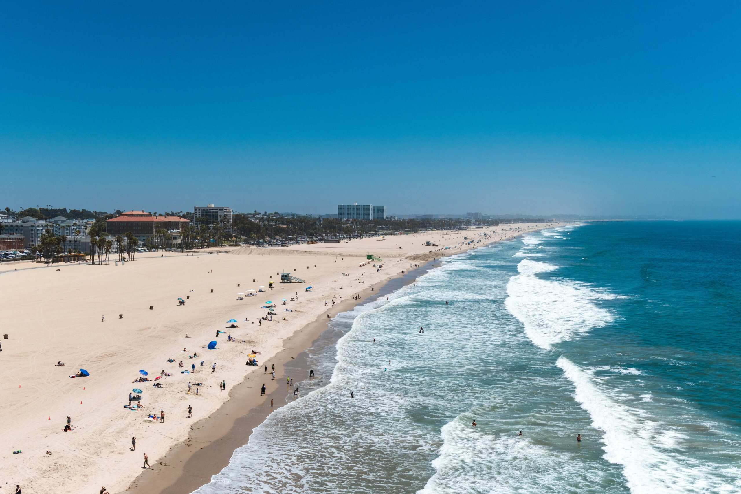 Aerial view of Santa Monica Beach with wide shoreline, pier, and the best Santa Monica boutique hotels and Santa Monica luxury hotels.